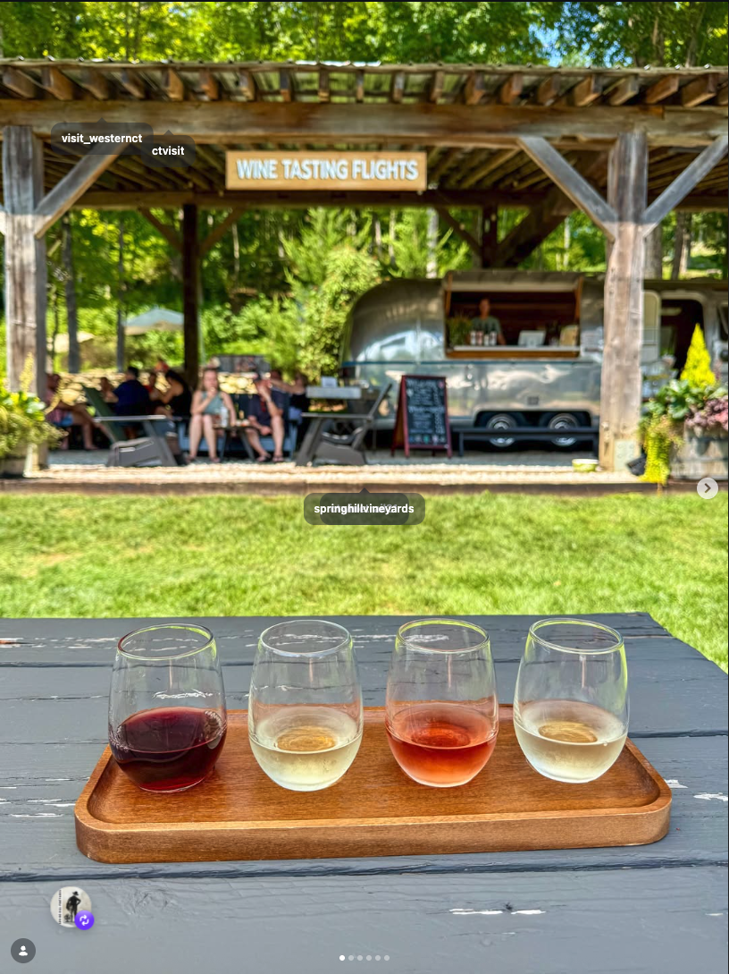 Single wine flight in foreground with the Airstream tasting room and WINE TASTING FLIGHTS sign behind