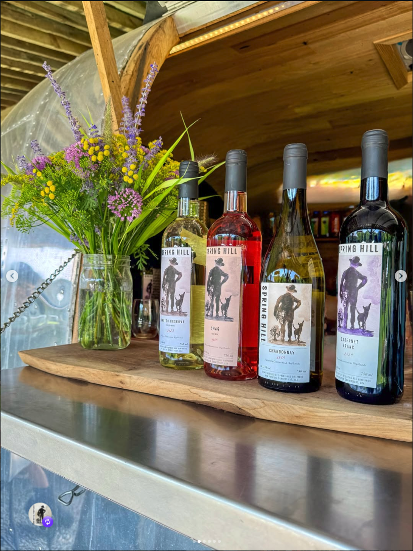 Five Spring Hill bottles lined up on the Airstream bar with a mason jar of wildflowers